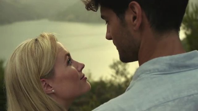 Young couple standing together by water's edge. 