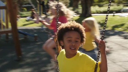 Slow motion of four children playing on swings in park. - Powered by Adobe