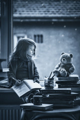 Adorable little girl, writing letter to Santa, sitting on a wind