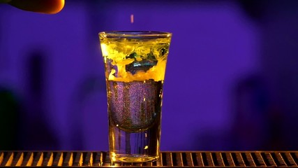 Barman mixing three different alcohol liquids, and using white