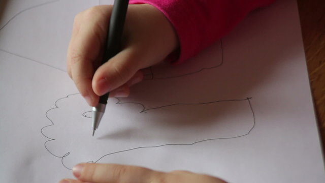 hand of a little girl draws a tree on paper
