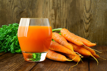 Carrot juice in glass and vegetables beside