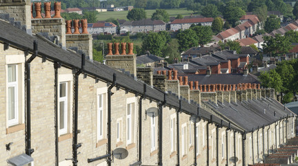 Red chimney tops atop row of stone built terraced houses in Lancashire England