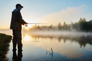 fisher fishing on foggy sunrise - obrazy, fototapety, plakaty