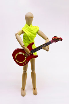 Wooden mannequin playing music on a guitar.