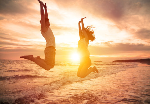 young happy couple jumping on beach