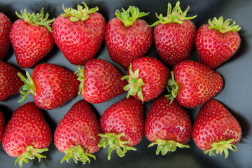 Close up of freshly picked strawberries on a black plate
