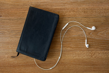 Contemporary image of a Bible with headphones. Hearing the voice