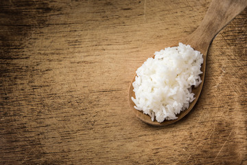 wooden spoon with white boiled rice on wood background