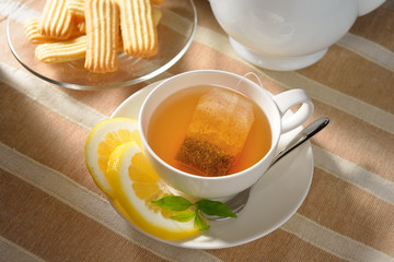 Cup of tea with lemon and cookies on table