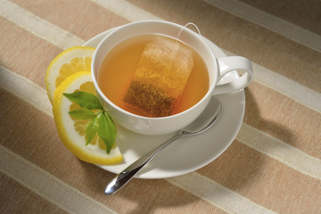 Cup of tea with tea bag and lemon on table