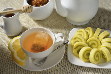 Cup of tea with lemon and cakes on table