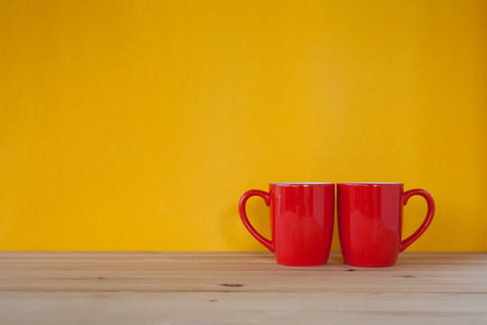 Two cups of coffee and stand together to be heart shape on yello
