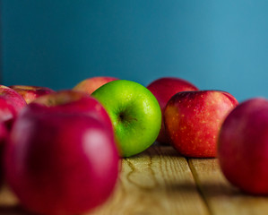 Green apple among red apples