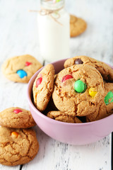 Cookies with colorful candy in bowl on white wooden background