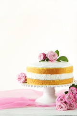Sweet cake on cake stand on white wooden background