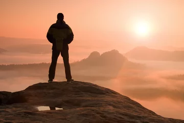 Fototapeten Alone hiker standing on top of a mountain and enjoying sunrise © rdonar