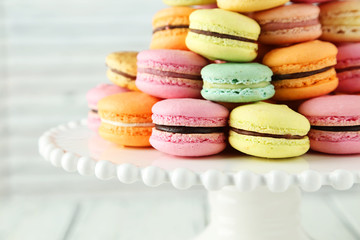 French colorful macarons on cake stand on white wooden backgroun