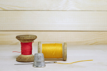 Old spool of thread with needle closeup. Tailor's work table. textile or fine cloth making.