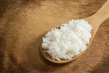 wooden spoon with white boiled rice on wood background