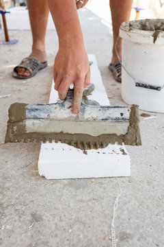 Construction worker puts a gypsum on styrofoam with spatula