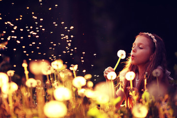 girl blowing a dandelion seeds flying