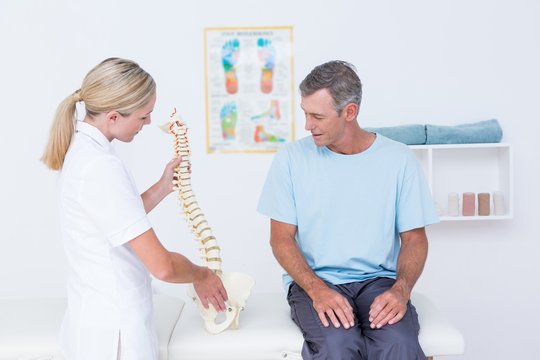 Doctor showing anatomical spine to her patient 