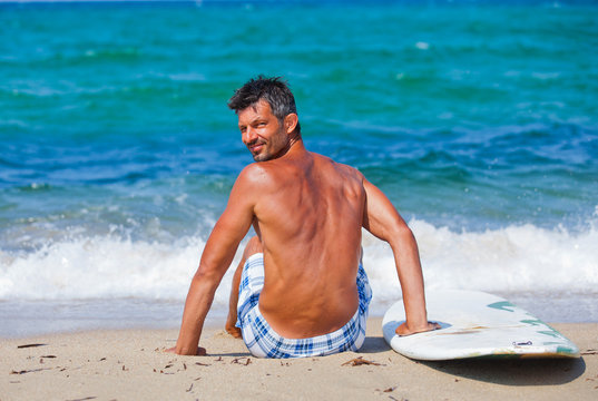 Man with his surfboard on the beach