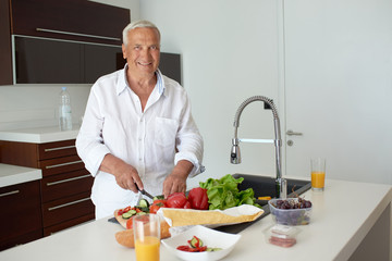 man cooking at home preparing salad in kitchen