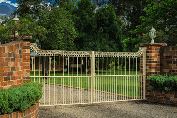 Wrought iron driveway entrance gates set in brick fence