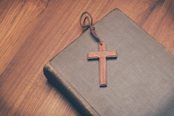 Vintage tone of wooden Christian cross necklace on holy Bible wi