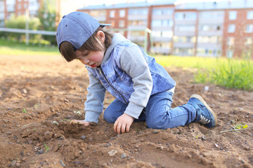 Cute little boy plays with sand outdoors