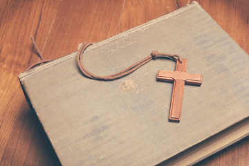 Vintage tone of wooden Christian cross necklace on holy Bible wi