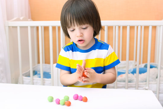 Little child (2 years) modelling playdough balls at home