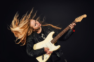 Obraz premium young woman with waving hair play electric guitar isolated on bl