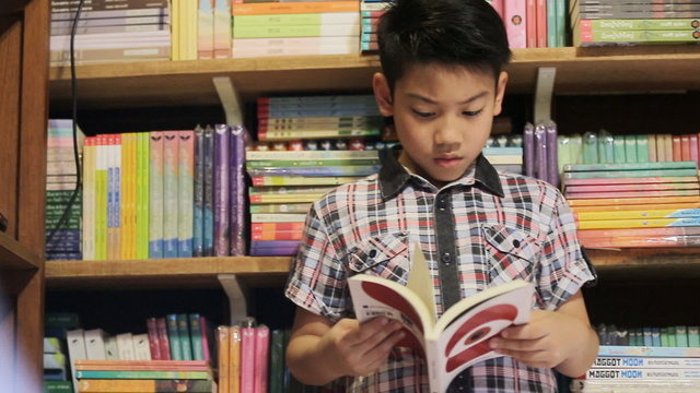 Asian boy reading book at home