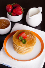Delicious pancakes with fresh strawberries on a plate, jam and m