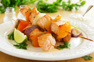 Shashlik of salmon with vegetables and white sauce.