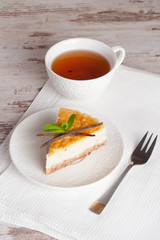 Vanilla cheesecake on a white plate and cup of tea, vertical