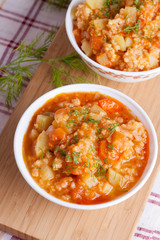 tomato soup with rice and vegetables in a white saucepan and bre