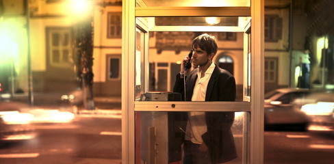 Man calling someone inside a phone box