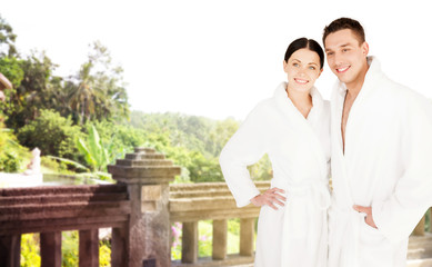 happy couple in bathrobes over spa hotel resort