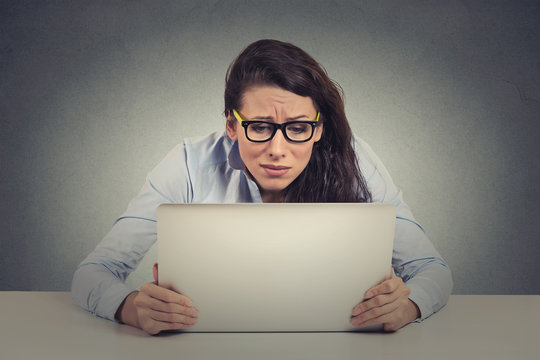 Stressed young woman looking at laptop screen