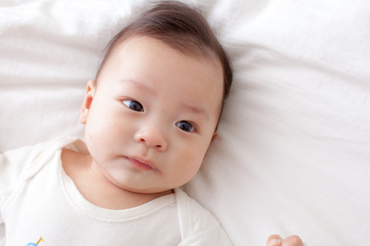 asian baby lay down on bed