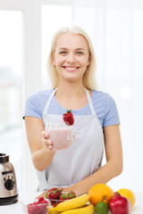 smiling woman holding glass of fruit shake at home