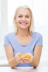 happy woman holding fish oil capsules at home