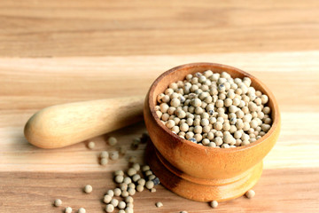 white pepper seeds on wooden background.