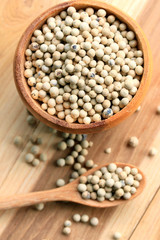 white pepper seeds on wooden background.