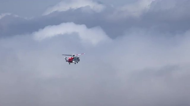A Coast Guard helicopter hovers above a mountain in the Scottish Highlands, UK