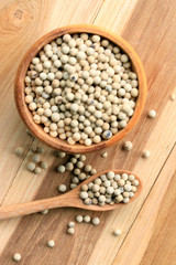 white pepper seeds on wooden background.